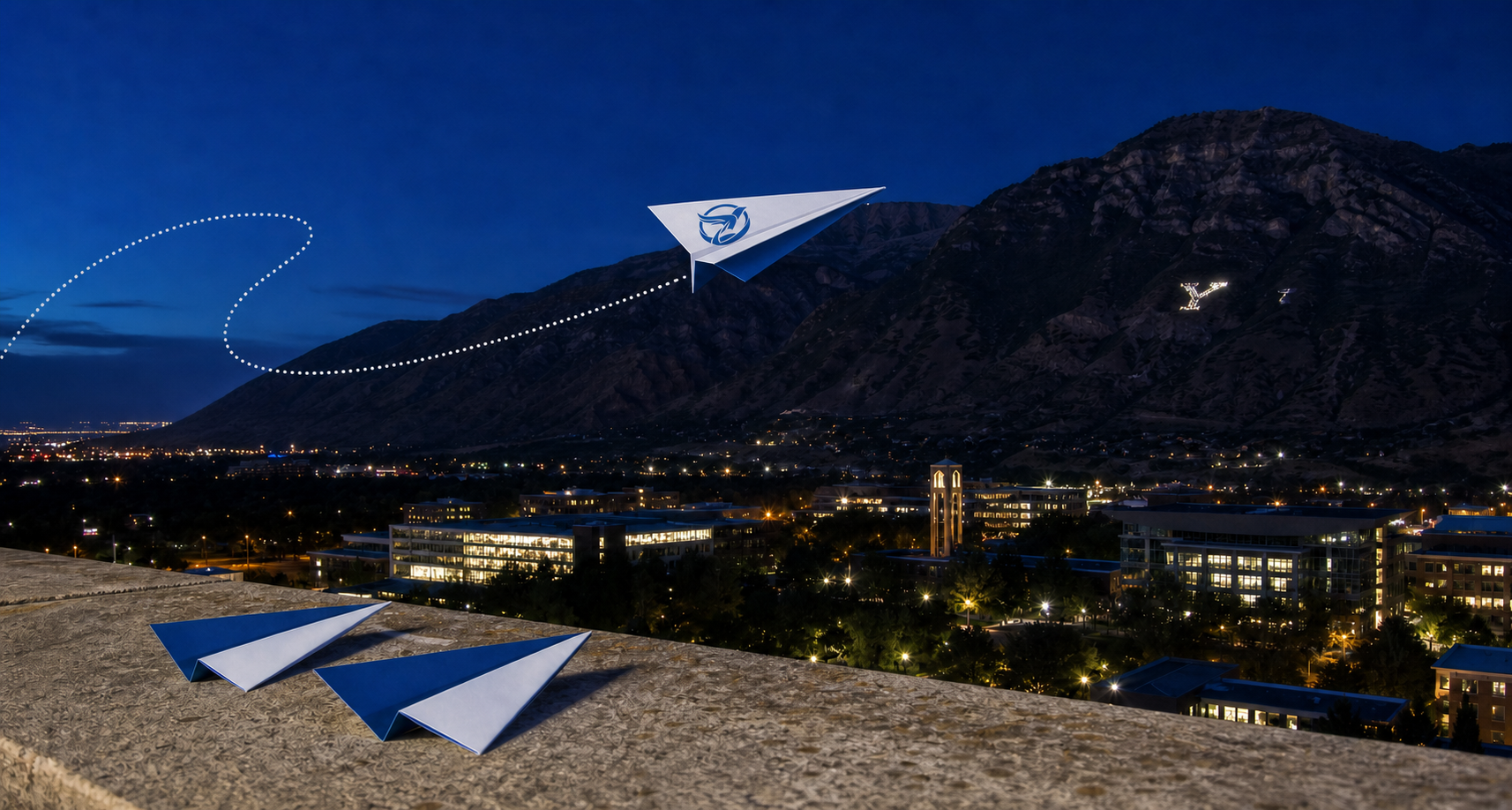 Y Mountain and the BYU campus at night with a logo-marked BirdsEye paper airplane flying overhead